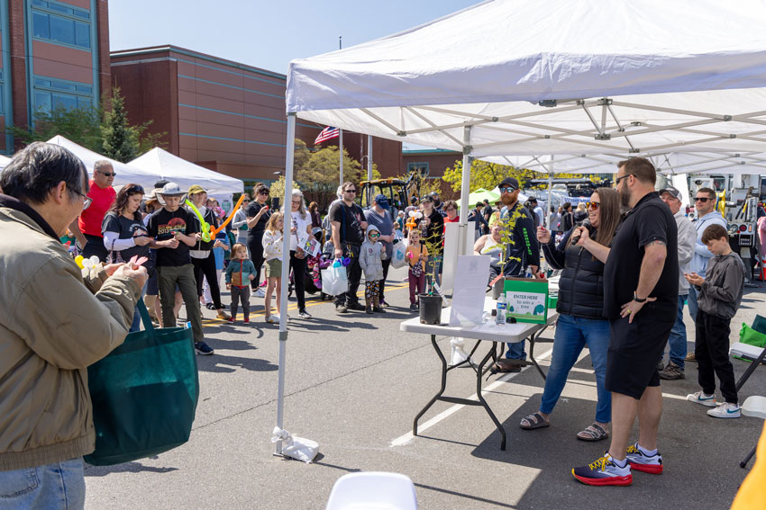 A man holds a microphone in front of a woman as she makes an announcement to an excited crowd