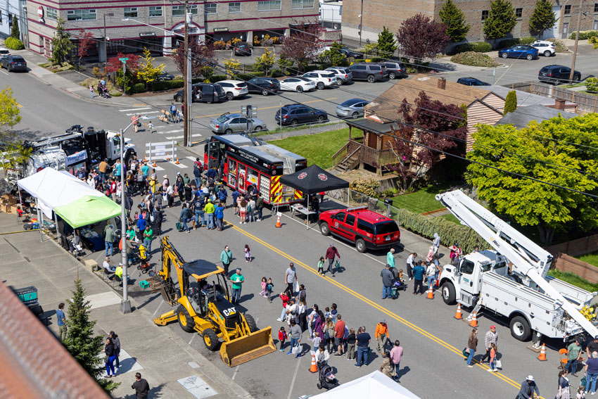 Aerial view of street with firetruck, bucket truck and other large vehicles showing pedestrians enjoying an outdoor event