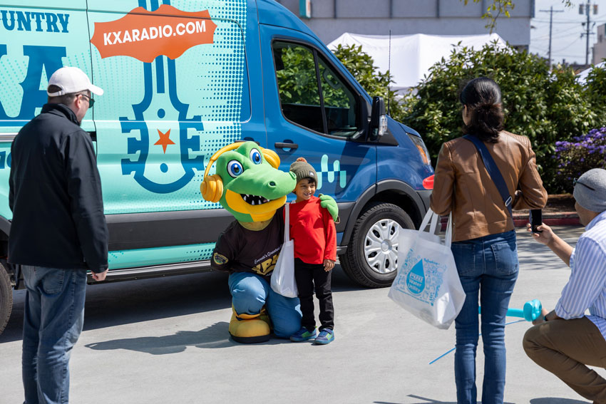 a crocodile mascot poses next to a smiling child wearing brightly colored clothing