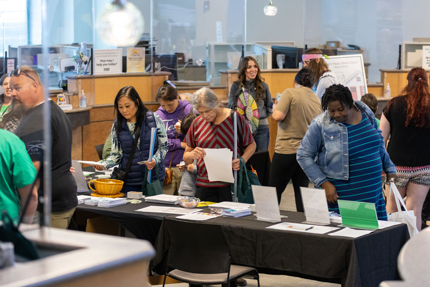 Customers study objects on a table while a spinning wheel game is held in the background