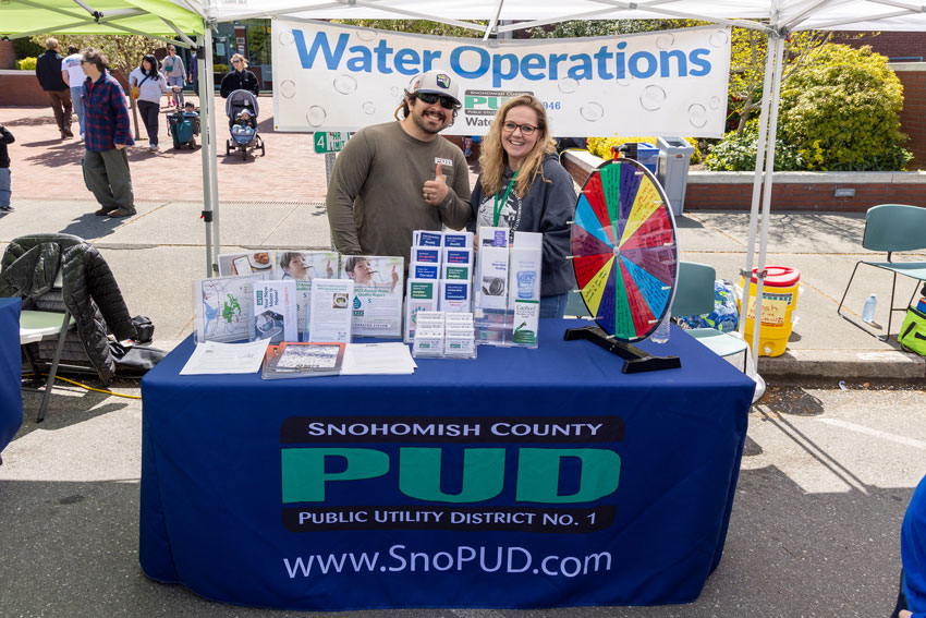 A smiling man and woman behind an informational table and a banner labeled Water Operations