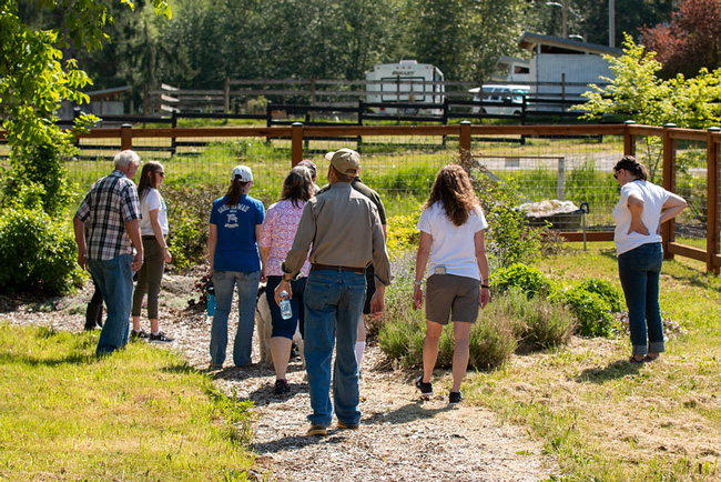 Visitors taking a gravel pathway through trees and bushes at Woods Creek Hydroelectric Project