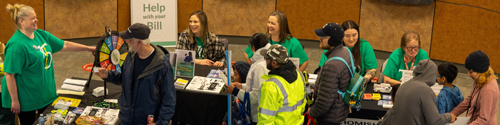 Customer service representatives laugh with customers at the Energy Block Party Customer Service tables
